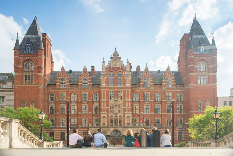 The front of the Royal College of Music building, with a group of students sitting on the steps going down to the college.